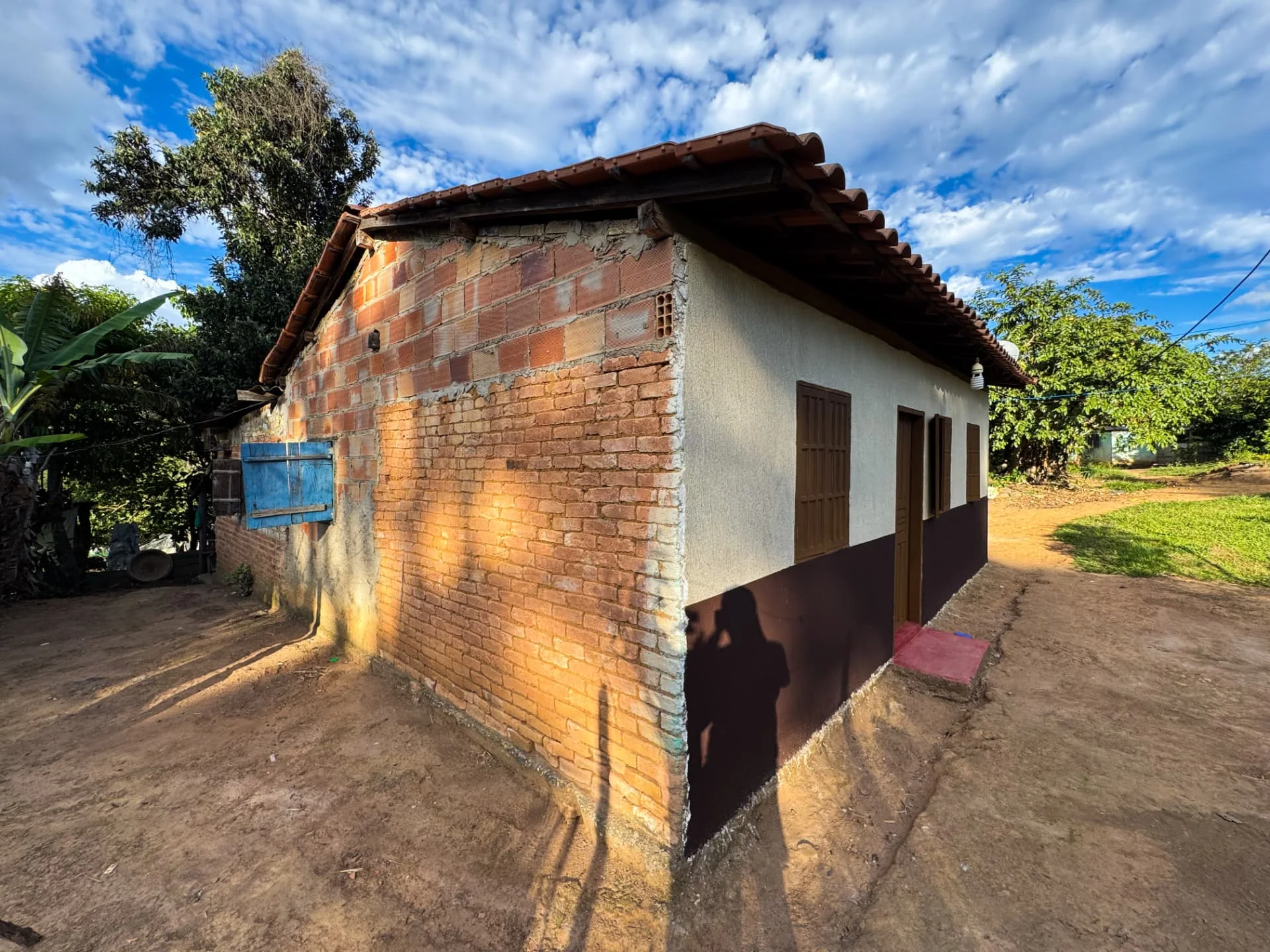 Casa da Vila Mumbuca durante a pintura: tijolo exposto ao lado da parede já pintada