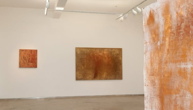 Vista da exposição “O avesso da terra”, com telas em tons de ocre e terracota nas paredes do Museu Mineiro